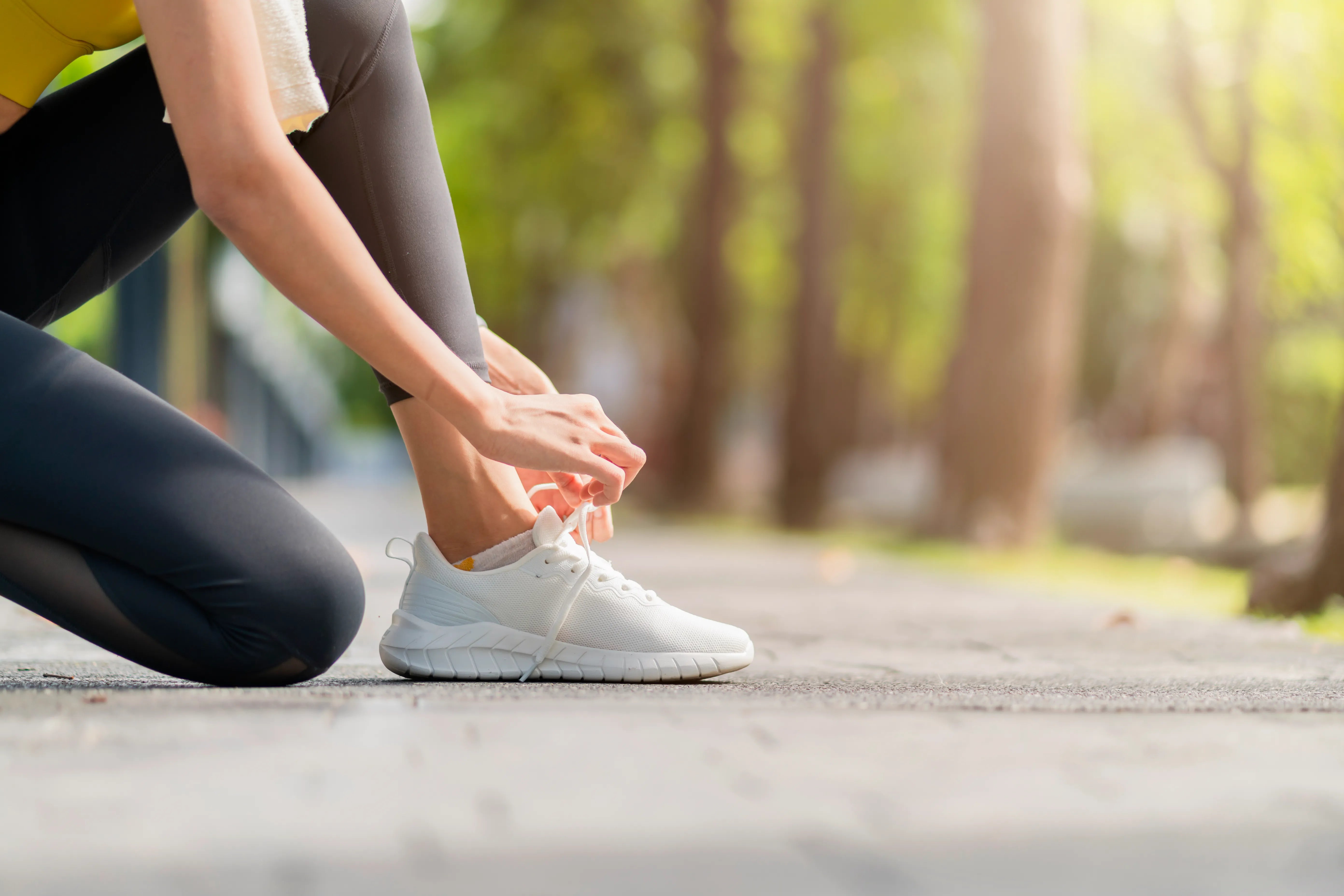 Asian female sport woman athlete tying laces for jogging on road in the park running shoes